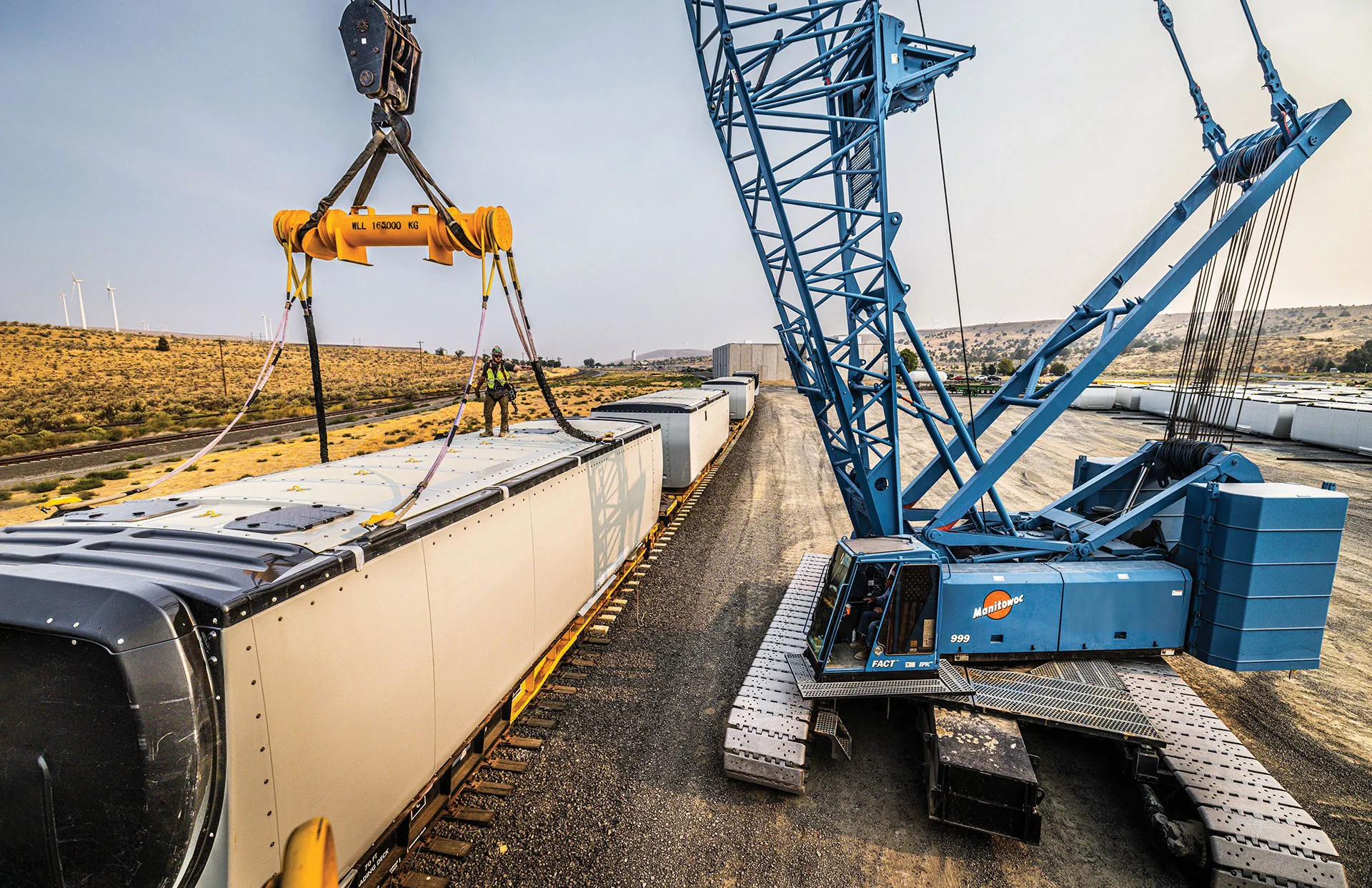 Omega Morgan Manitowoc 999 crawler crane lifting cargo from rail car